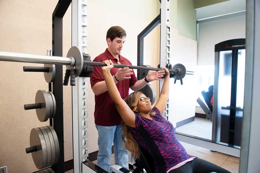 researcher assisting patient to do bench presses